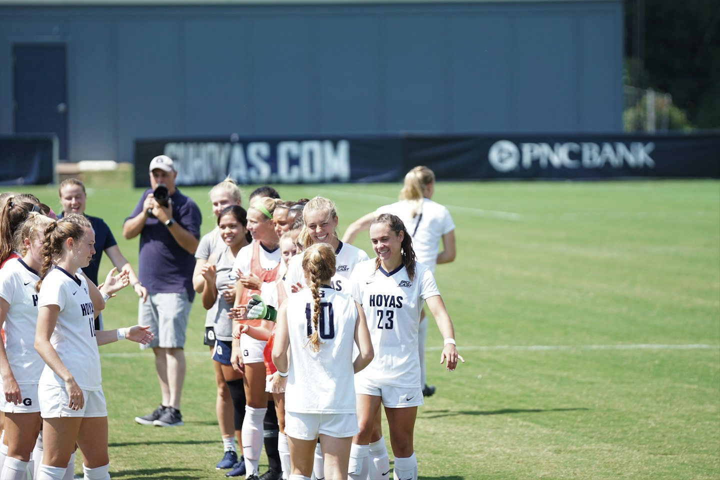 Diverse young women talking and smiling on a grassy field.