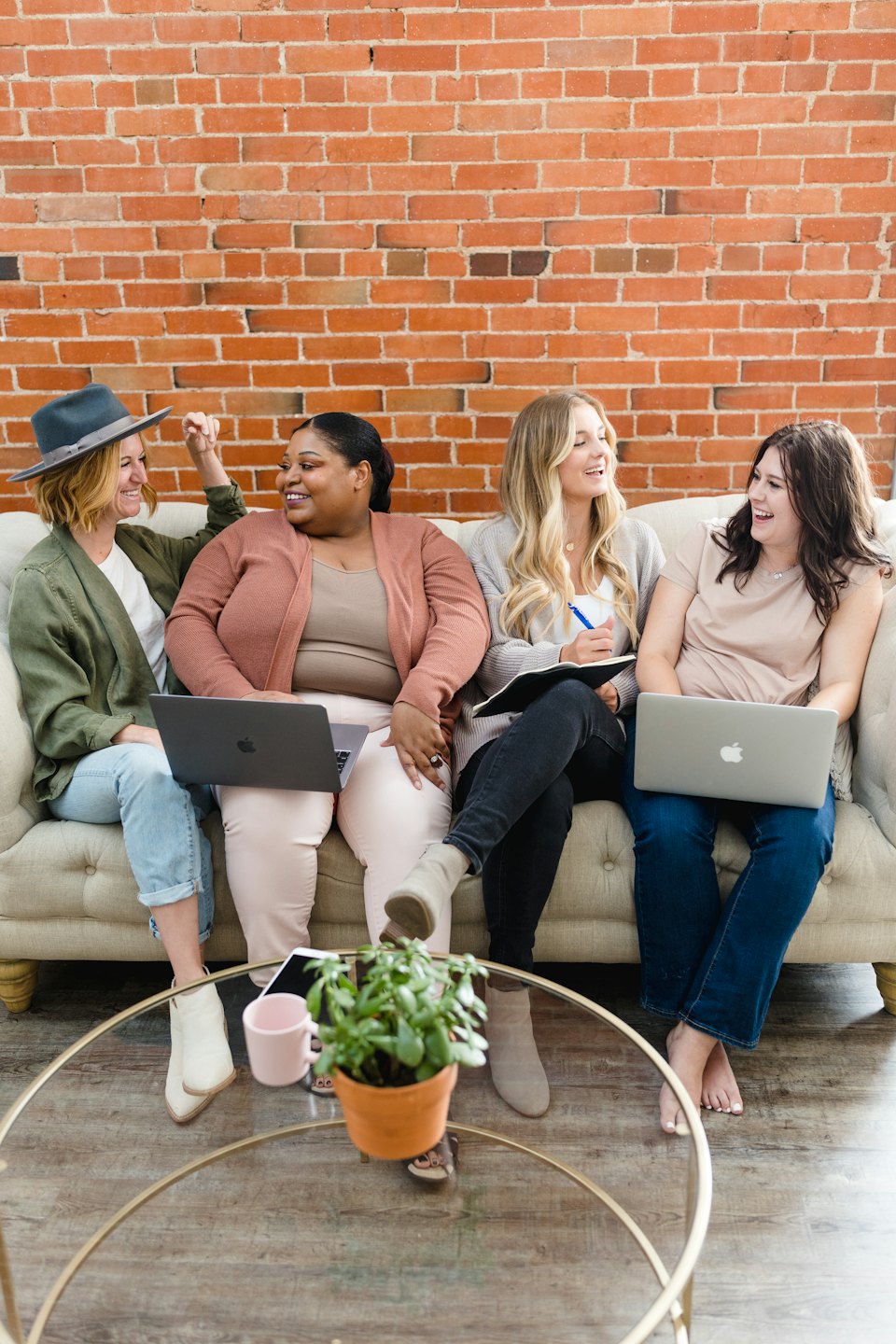 Four diverse women collaborating on laptops and notes in a bright office.