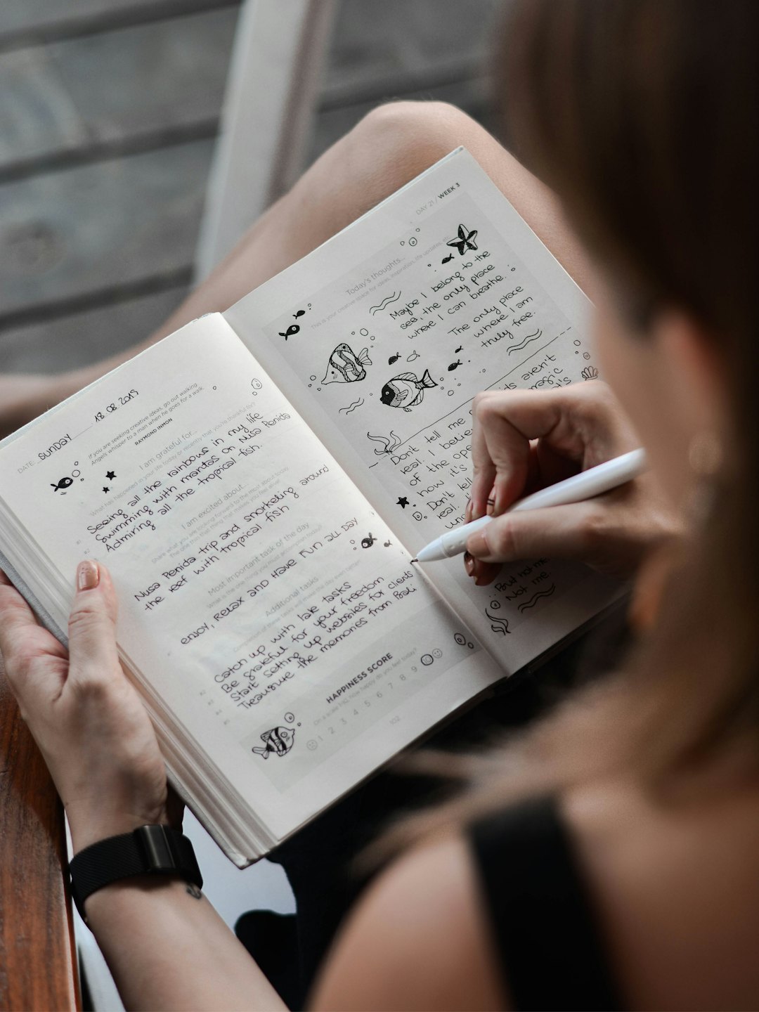Woman writing gratitude lists and doodles in a planner.